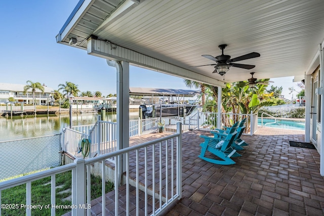 view of patio / terrace featuring a fenced in pool, a water view, a ceiling fan, fence, and a dock