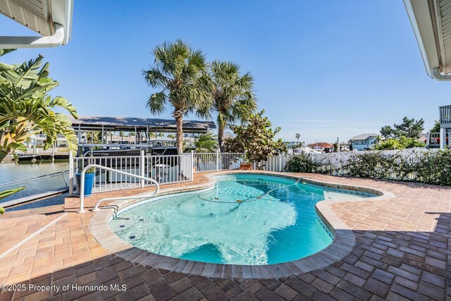 view of pool with a patio area, a water view, a fenced backyard, and a fenced in pool