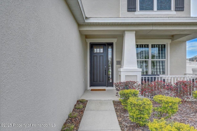 entrance to property with stucco siding and a porch