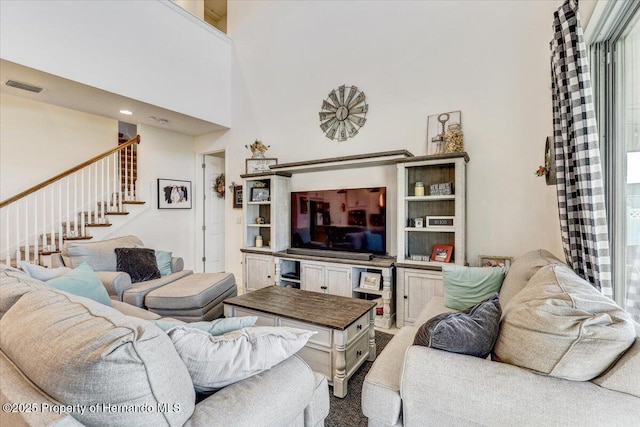 living area featuring visible vents, a high ceiling, and stairway