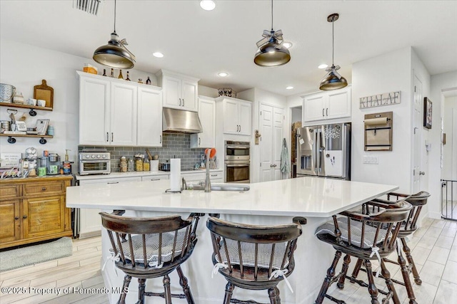 kitchen featuring visible vents, backsplash, under cabinet range hood, light countertops, and stainless steel appliances