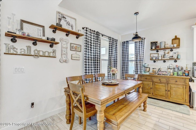 dining space featuring baseboards and wood tiled floor