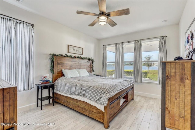 bedroom featuring light wood-type flooring, baseboards, and a ceiling fan