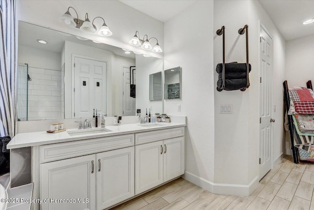 bathroom featuring double vanity, wood finish floors, baseboards, and a sink