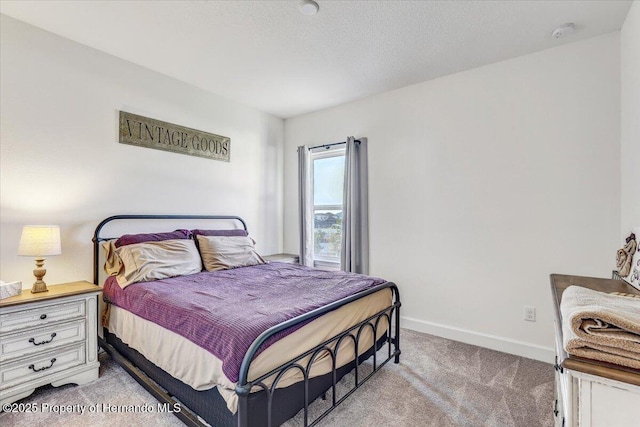 bedroom featuring light colored carpet, a textured ceiling, and baseboards