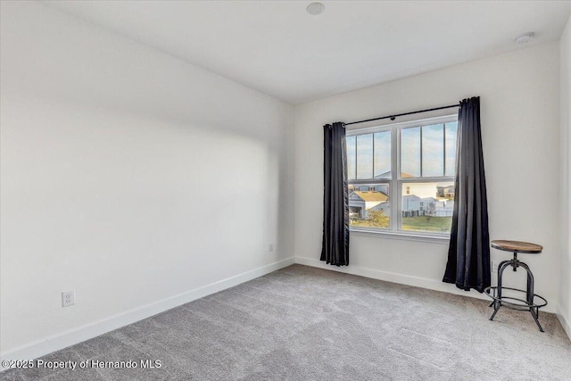 carpeted empty room featuring baseboards