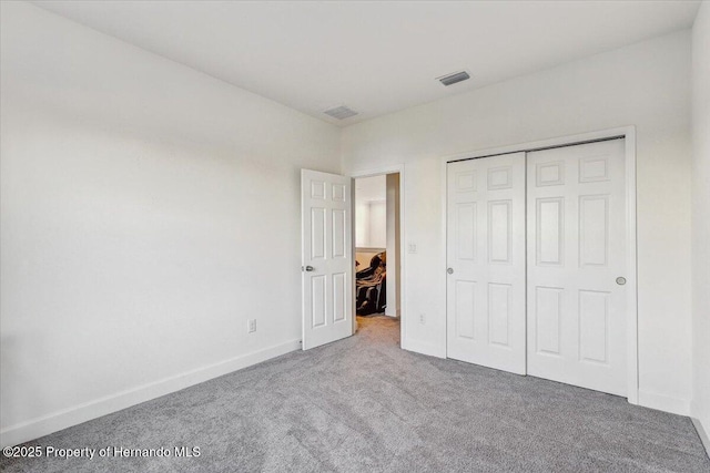 unfurnished bedroom featuring a closet, baseboards, visible vents, and carpet floors