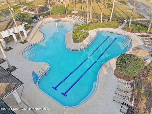 community pool with a patio area and fence