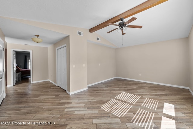 spare room with lofted ceiling with beams, light wood finished floors, visible vents, and baseboards