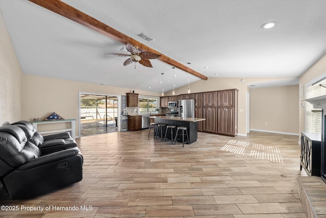 living area featuring lofted ceiling with beams, wood finish floors, a ceiling fan, and baseboards