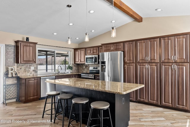 kitchen featuring lofted ceiling with beams, a kitchen island, light stone counters, stainless steel appliances, and pendant lighting