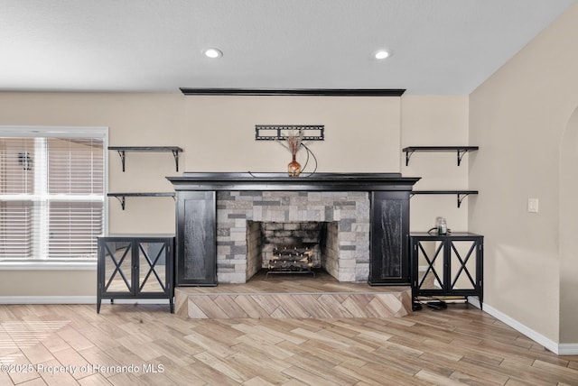 living room featuring light wood-type flooring, baseboards, a fireplace, and arched walkways