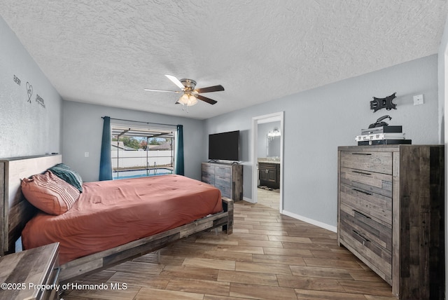 bedroom featuring a textured ceiling, a ceiling fan, baseboards, wood tiled floor, and ensuite bath