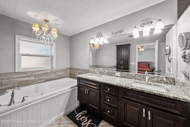 bathroom with double vanity, a sink, a textured ceiling, and ensuite bathroom