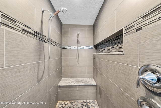 bathroom featuring a textured ceiling and a tile shower