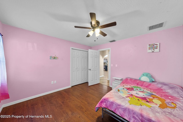 bedroom with baseboards, a closet, visible vents, and dark wood-type flooring