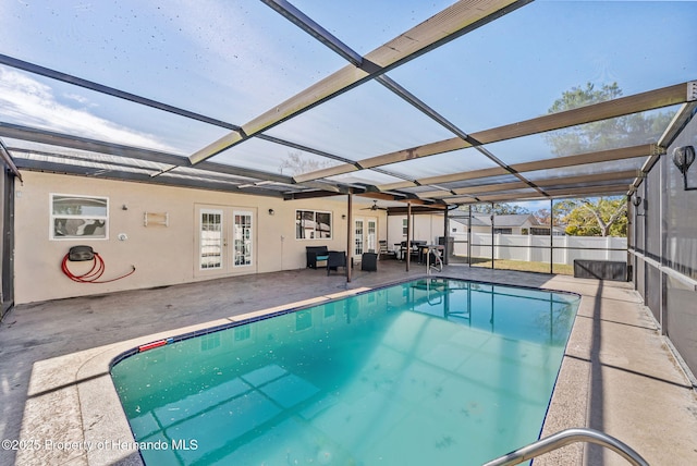 view of swimming pool with glass enclosure, fence, french doors, a fenced in pool, and a patio area