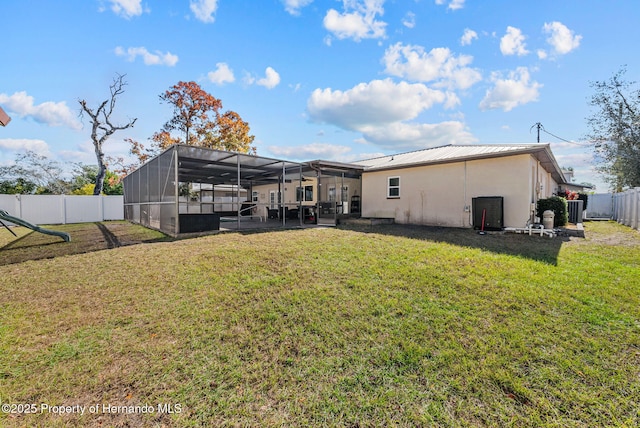 back of house featuring a yard, a lanai, and stucco siding