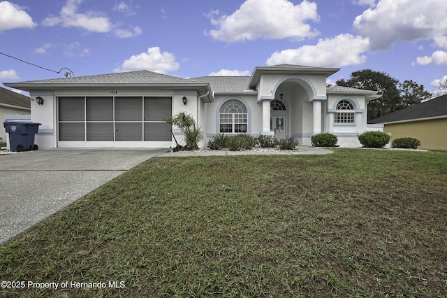 view of front of house featuring driveway, an attached garage, a front lawn, and stucco siding