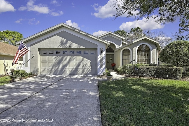 ranch-style house with a garage, a front yard, driveway, and stucco siding