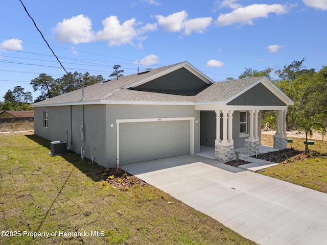 view of front of property with cooling unit, roof with shingles, an attached garage, stucco siding, and a front lawn