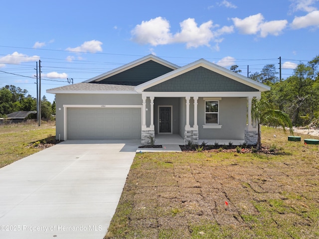 craftsman-style home with stucco siding, a front lawn, driveway, a porch, and a garage