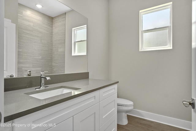 bathroom featuring toilet, vanity, baseboards, and wood finished floors