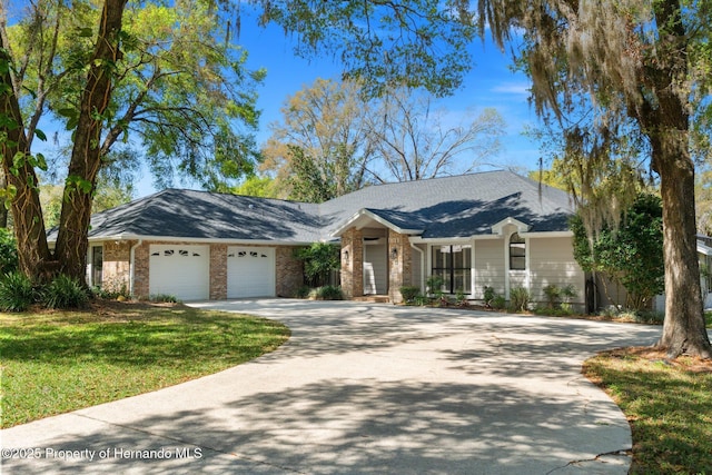 view of front of property featuring a front yard, brick siding, a garage, and driveway