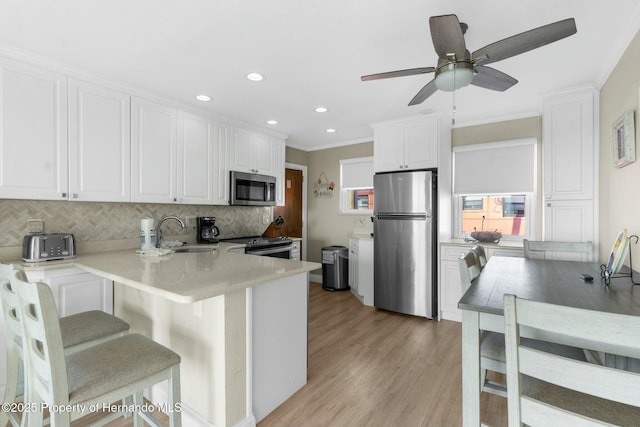 kitchen with decorative backsplash, stainless steel appliances, light wood-type flooring, white cabinetry, and a sink