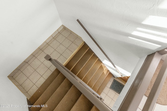 stairs featuring tile patterned flooring and a textured ceiling