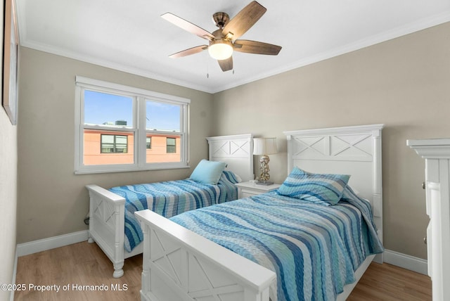 bedroom with light wood-type flooring, crown molding, and baseboards