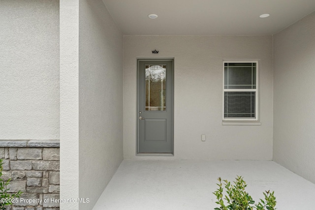 doorway to property featuring stone siding and stucco siding