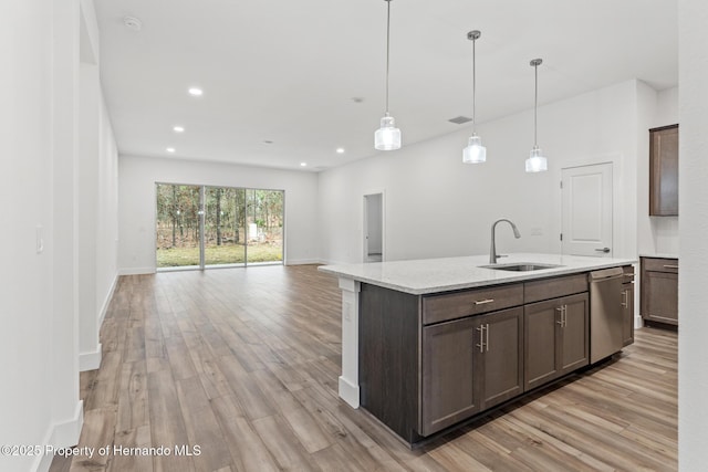 kitchen with stainless steel dishwasher, open floor plan, light wood finished floors, and a sink