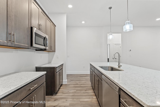 kitchen with light stone countertops, recessed lighting, a sink, stainless steel appliances, and light wood-style floors