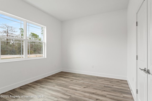 spare room featuring light wood finished floors and baseboards