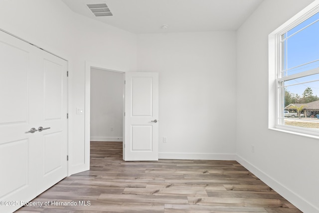 spare room featuring visible vents, baseboards, and light wood-style floors