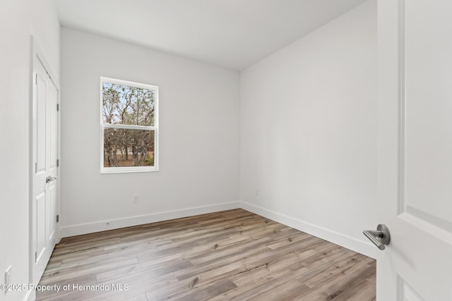 unfurnished room with light wood-type flooring and baseboards