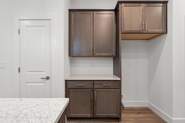 kitchen featuring light countertops, dark brown cabinets, wood finished floors, and baseboards