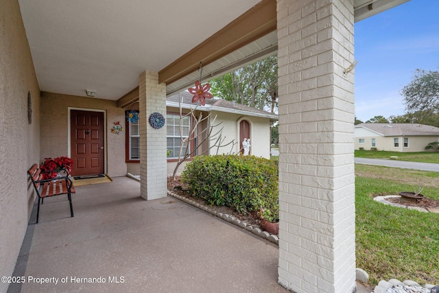 property entrance featuring a porch and stucco siding