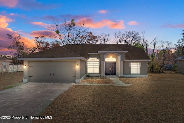 single story home with driveway, a shingled roof, stucco siding, an attached garage, and a front yard