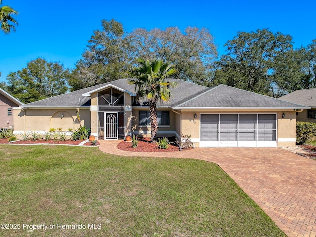 mid-century home featuring decorative driveway, a front lawn, and stucco siding