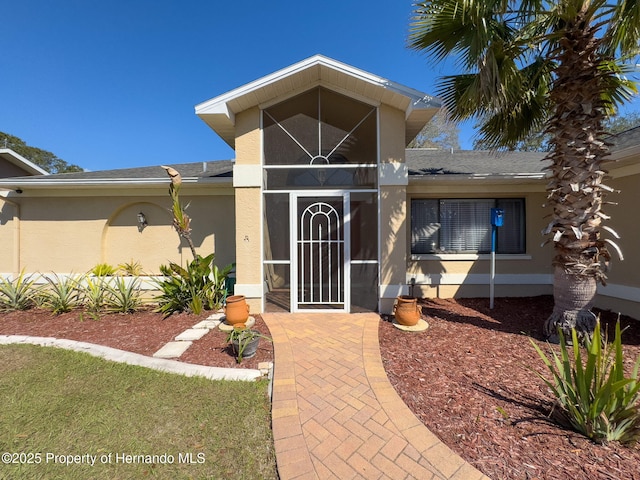 entrance to property with roof with shingles and stucco siding