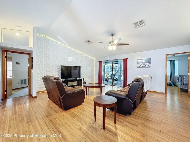 living room with lofted ceiling, light wood-style floors, and visible vents