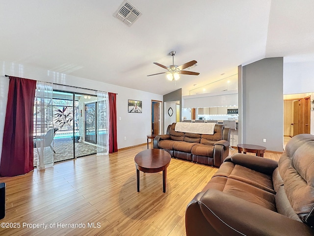 living area featuring vaulted ceiling, light wood-type flooring, visible vents, and a ceiling fan