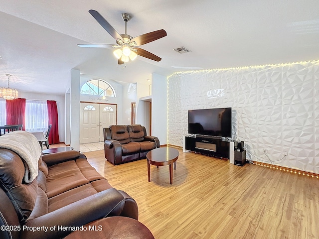 living area with light wood finished floors, visible vents, vaulted ceiling, and a ceiling fan