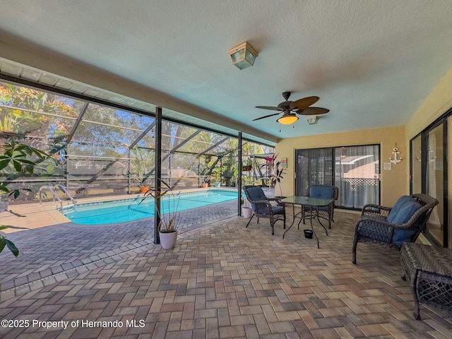 pool with a ceiling fan, glass enclosure, and a patio area