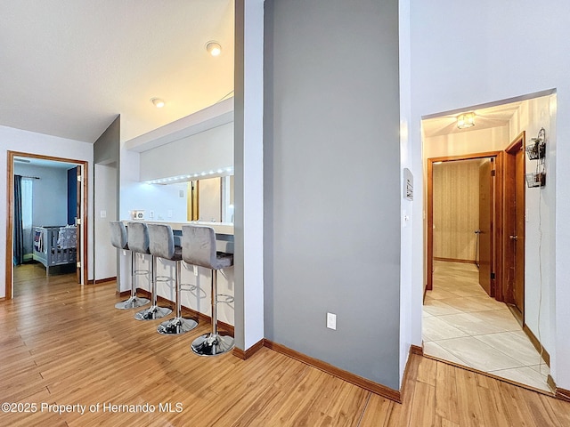 hall with light wood finished floors, a high ceiling, and baseboards