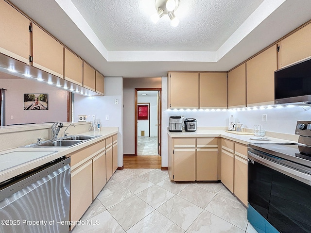 kitchen featuring appliances with stainless steel finishes, a raised ceiling, light countertops, and a textured ceiling