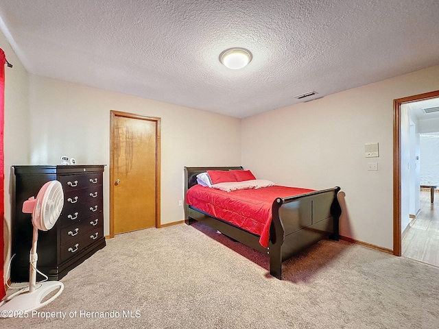 bedroom featuring carpet floors, visible vents, a textured ceiling, and baseboards