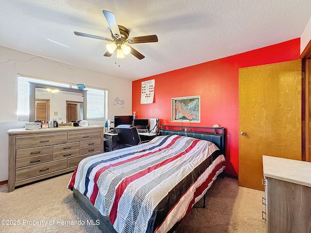 bedroom featuring a textured ceiling, a ceiling fan, and light colored carpet